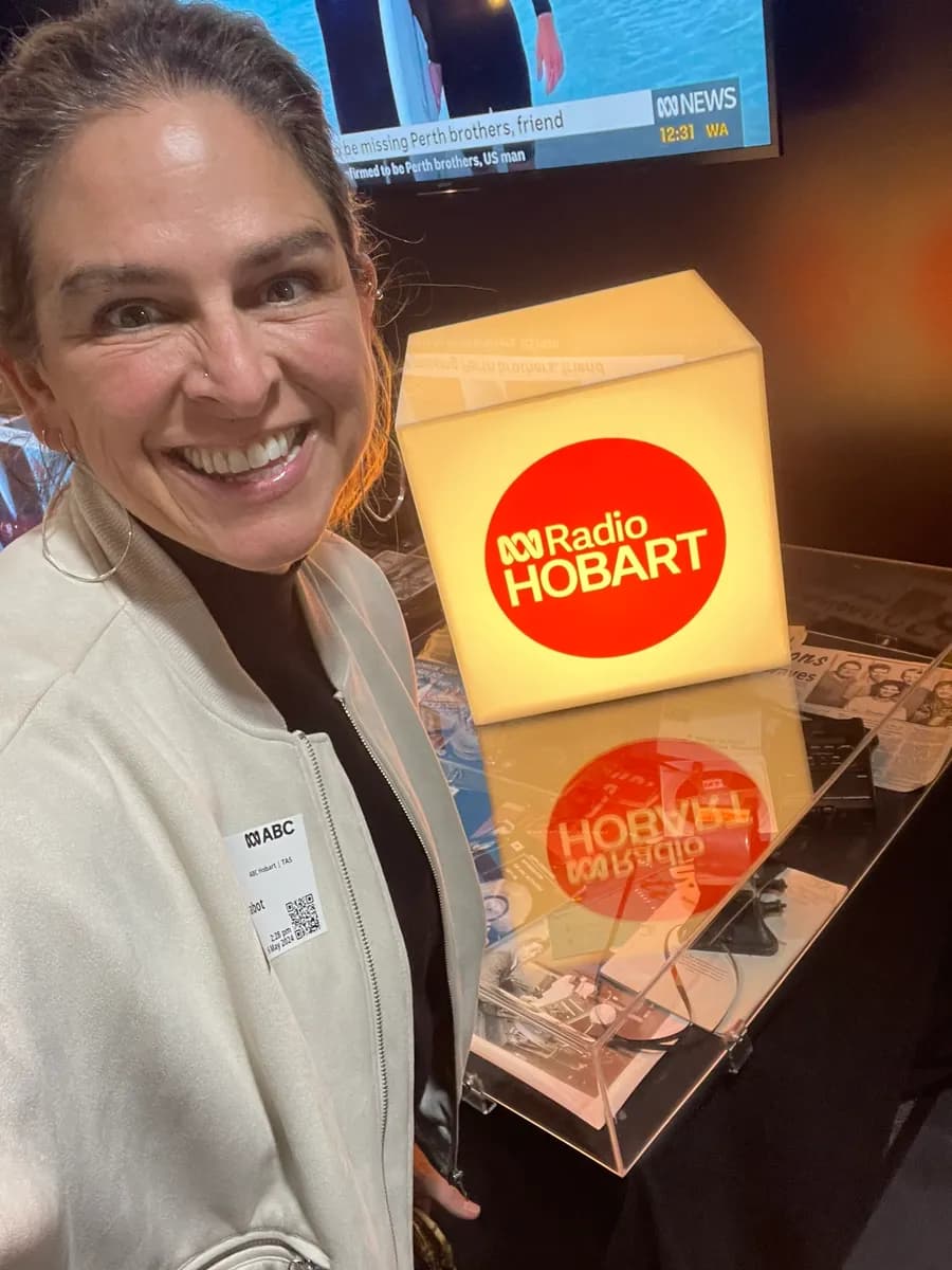 Dr Rebecca Chabot in the ABC Radio Hobart studio, beside the station's illuminated sign