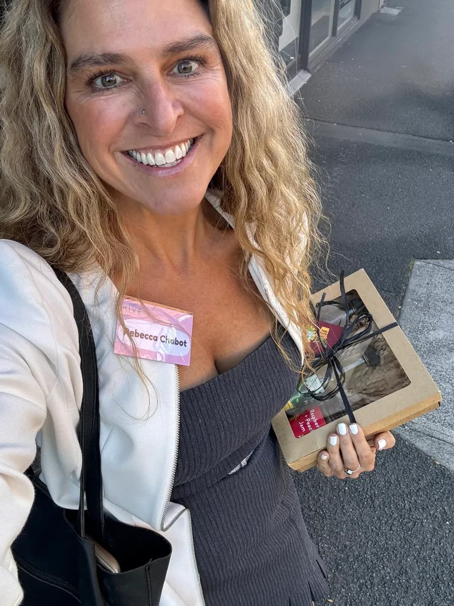 Dr Rebecca Chabot wearing a name badge and white jacket, holding a book on a city street