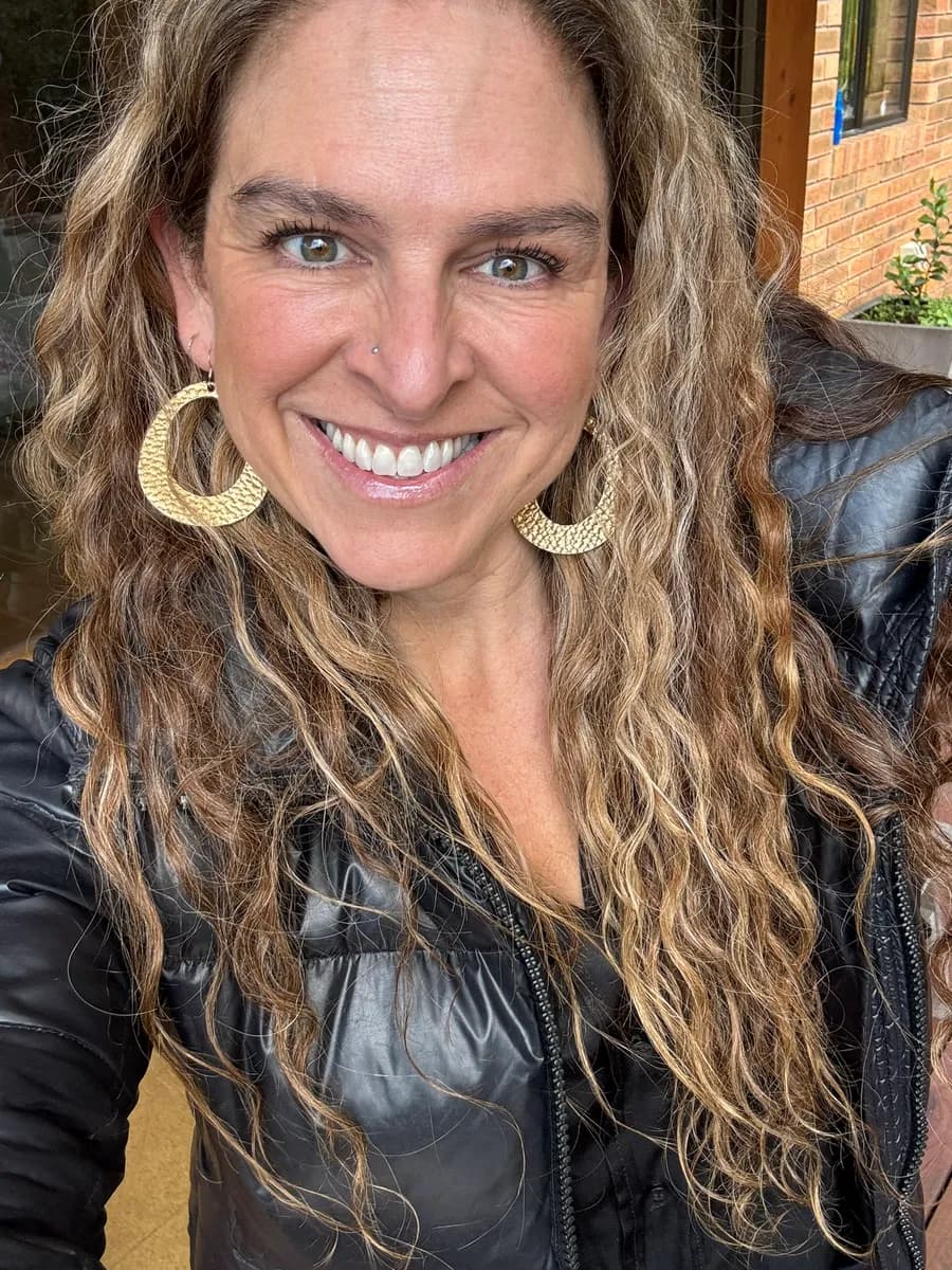 Dr Rebecca Chabot outdoors in a leather jacket and gold hoop earrings