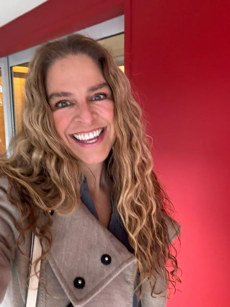 Dr Rebecca Chabot smiling in a beige coat beside a red doorway