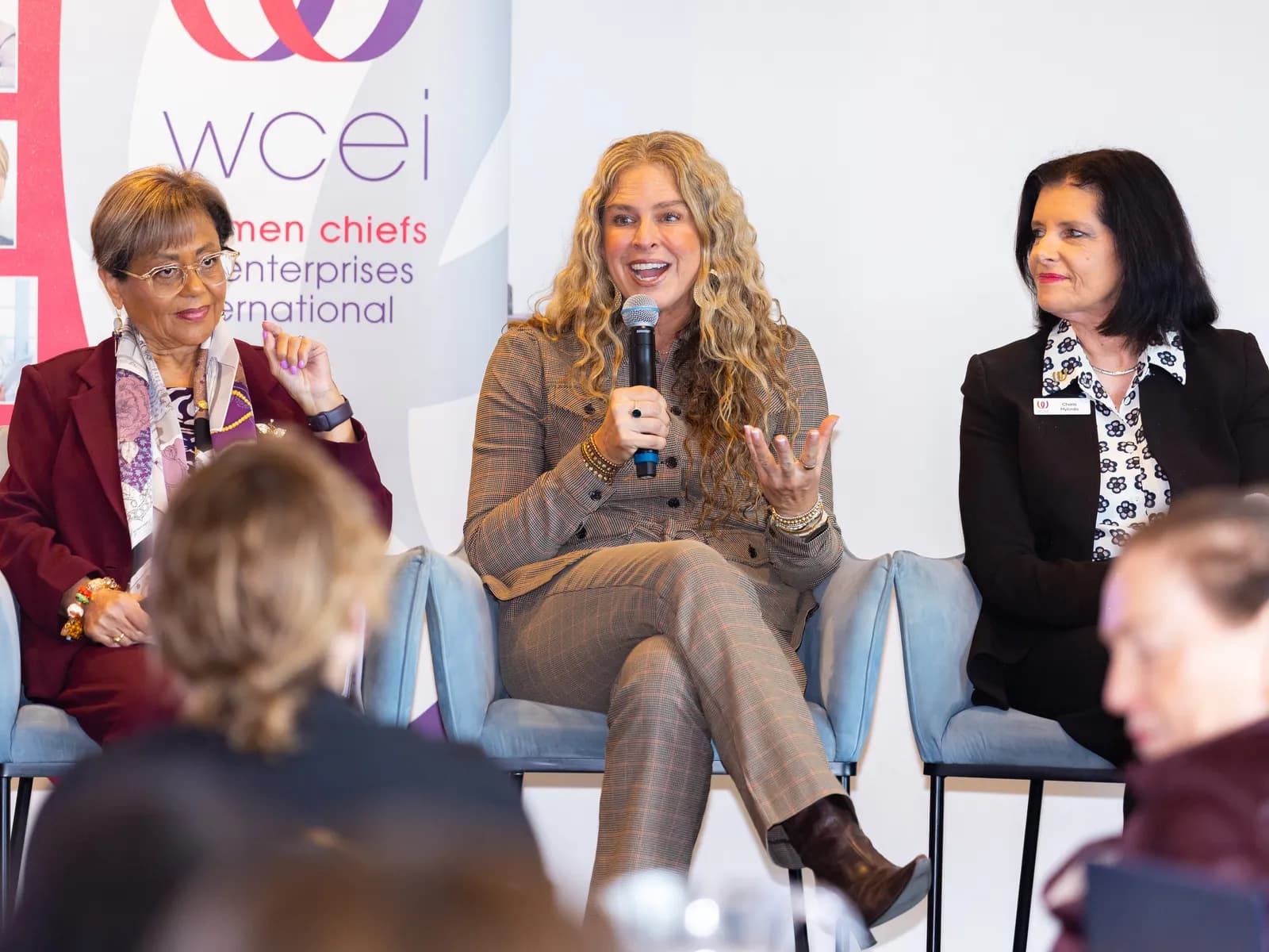 Dr Rebecca Chabot answering a question with a microphone on a conference panel, seated between two other panellists