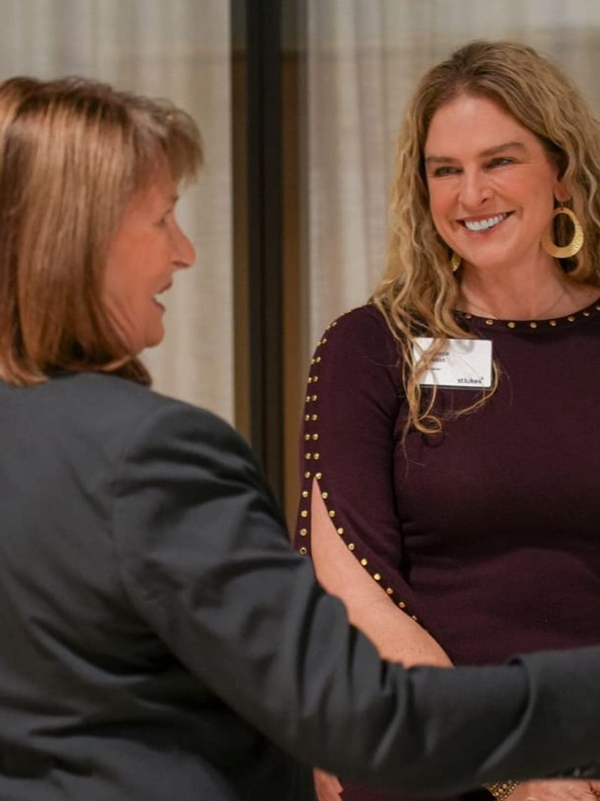 Dr Rebecca Chabot, wearing a St Luke's name badge, smiling mid-conversation with a guest at the St Luke's Leaders Forum
