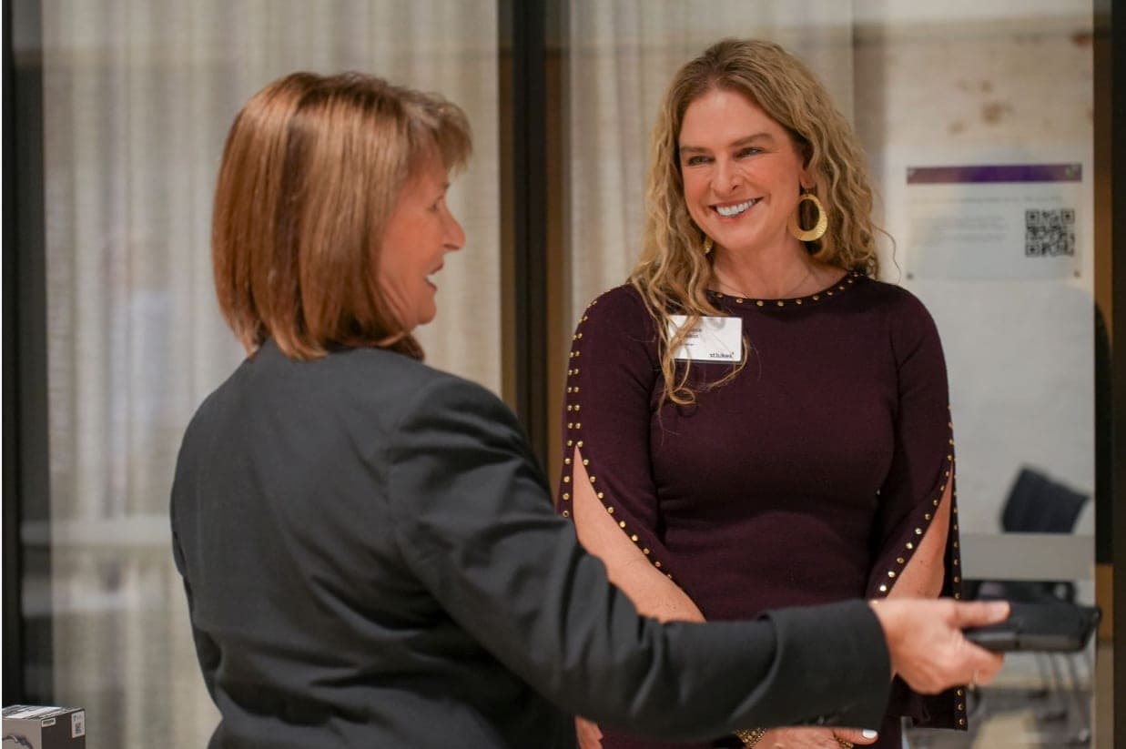 Dr Rebecca Chabot, wearing a St Luke's name badge, smiling mid-conversation with a guest at the St Luke's Leaders Forum